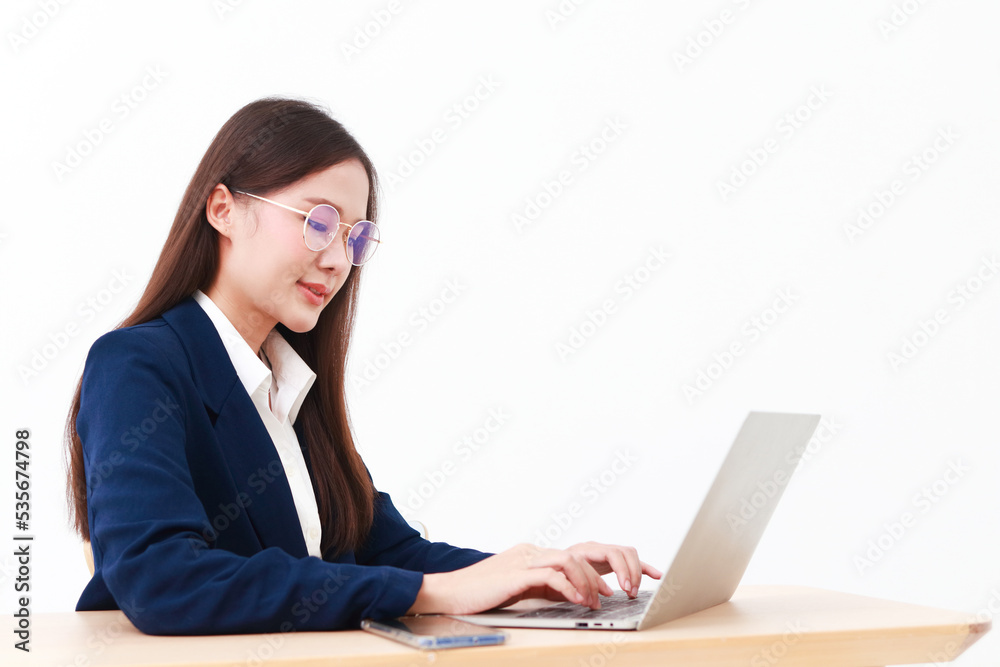 female manager wearing a blue suit sitting at the desk She is wearing glasses typing data on her laptop computer. Concept of businesswoman, entrepreneurs. copy space. white background female manager wearing a blue suit sitting at the desk She is wearing glasses typing data on her laptop computer. Concept of businesswoman, entrepreneurs. copy space. white background