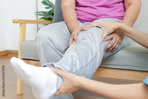 Asian female doctor doing physical therapy for elderly people with leg pain. Concept of physical rehabilitation for the elderly. Elderly health care and physical therapy center