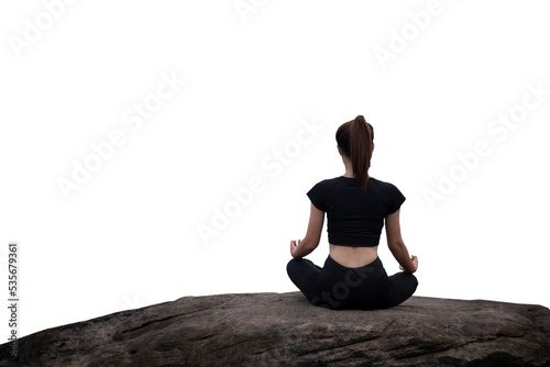 The back of a woman wearing sportswear doing a yoga pose on the rocks.