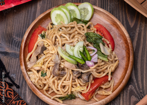 Mie Goreng Jawa or bakmi jawa or java noodle with spoon and fork. Indonesian traditional street food noodles from central java or Yogyakarta, Indonesia on wood background. Selective Focus. Close Up