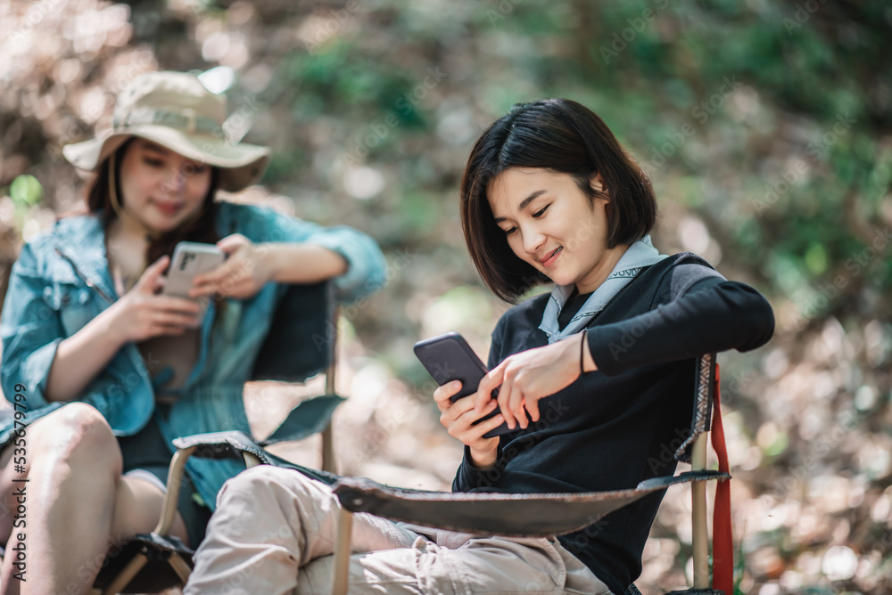 Obraz premium Group of girl friends with smartphone while camping in park