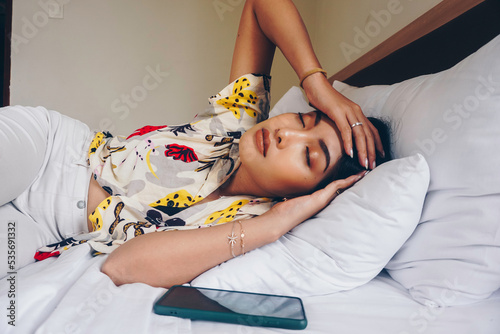 Young attractive woman in the bedroom, she is lying on the side and showing tired gesture