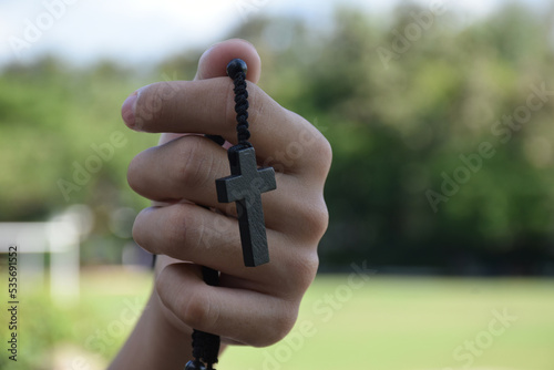 Asian young Christian boy shows his wooden rosary necklace with a cross  soft and selective focus  concept for showing pride in being a Christian to other people around the world.