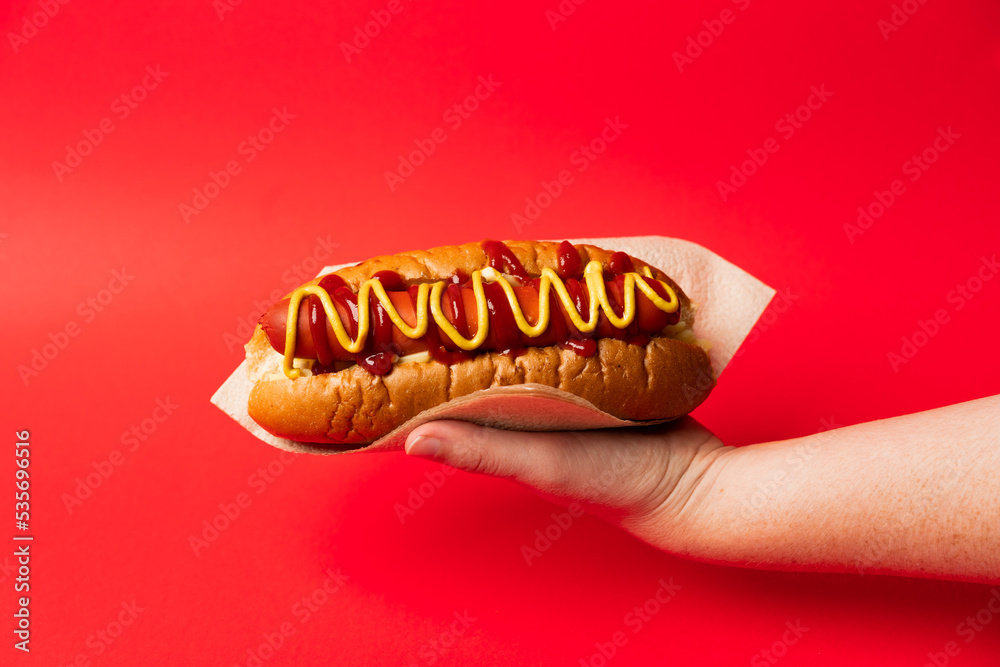 American Hotdog held in hand with Red background American Hotdog held in hand with Red background