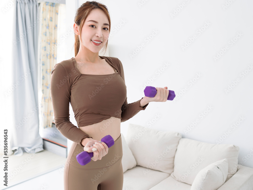 smiling young woman with dumbbells exercising at home smiling young woman with dumbbells exercising at home