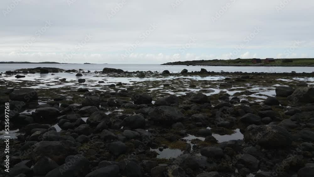 Walking over the stone boulder studded beach in Norway towards the open ocean Fjord at a coastal trail Walking over the stone boulder studded beach in Norway towards the open ocean Fjord at a coastal trail
