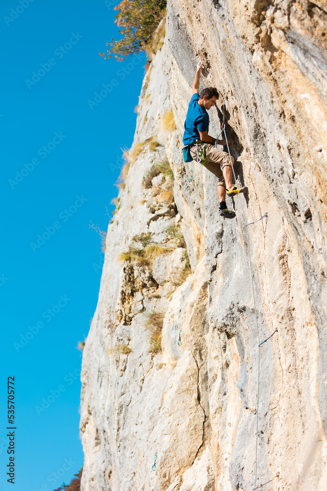 A strong man climbs a rock