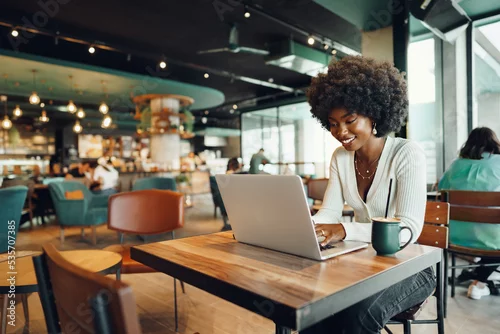 Obraz Smiling young african woman sitting with laptop in cafe