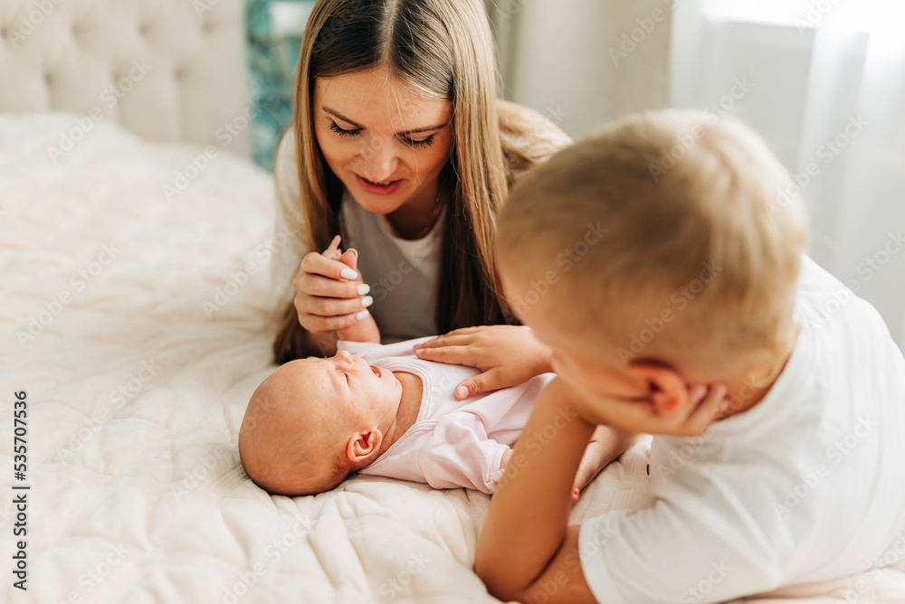 Lifestyle family portrait of parents with newborn baby child and older son. Happiness and love at home indoors Lifestyle family portrait of parents with newborn baby child and older son. Happiness and love at home indoors