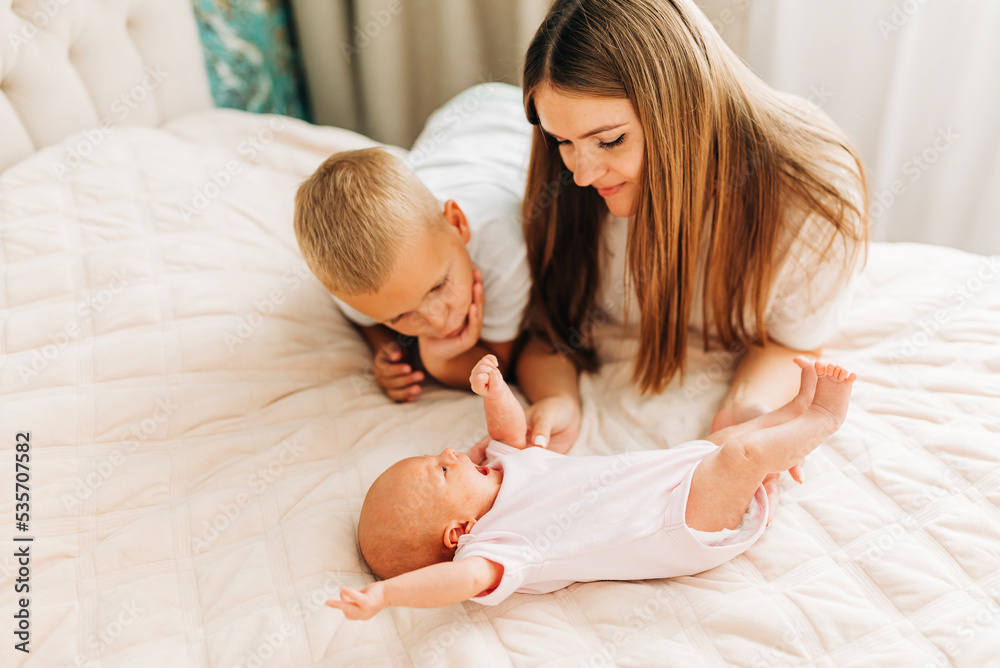 Lifestyle family portrait of parents with newborn baby child and older son. Happiness and love at home indoors Lifestyle family portrait of parents with newborn baby child and older son. Happiness and love at home indoors