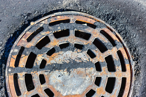 A cast-iron storm sewer hatch on the road before laying the asphalt pavement poured with bitumen. Drainage of rainwater from the road surface. Close-up.