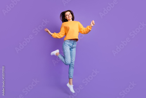 Full body length photo of young attractive nice girl dancing celebrating trampoline jump hands up good mood isolated on purple color background