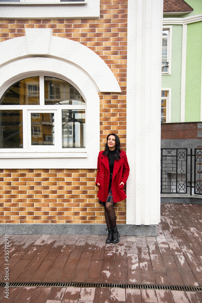 brunette woman in red coat with red lips walking in autumn Kyiv city