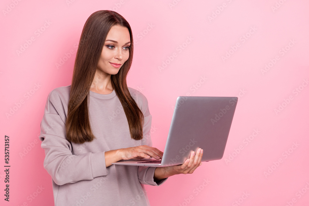 Portrait of pretty positive girl hold use wireless netbook networking isolated on pink color background Portrait of pretty positive girl hold use wireless netbook networking isolated on pink color background