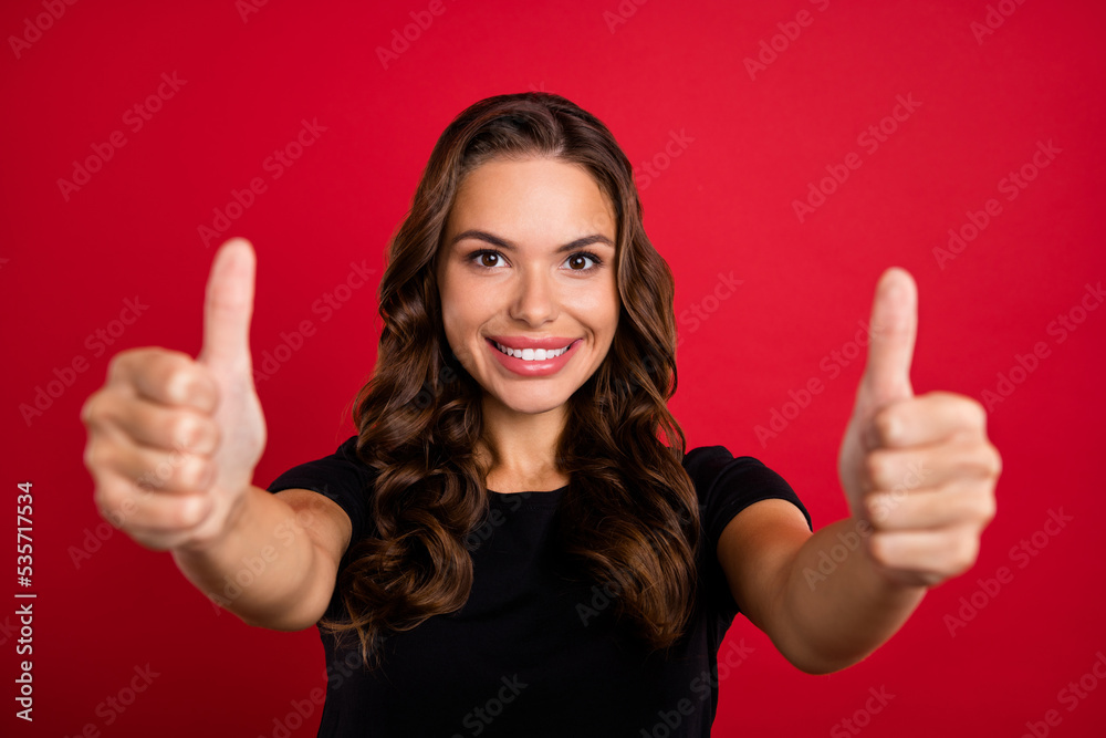 Photo of shiny sweet young lady dressed black t-shirt smiling showing two thumbs up isolated red color background Photo of shiny sweet young lady dressed black t-shirt smiling showing two thumbs up isolated red color background