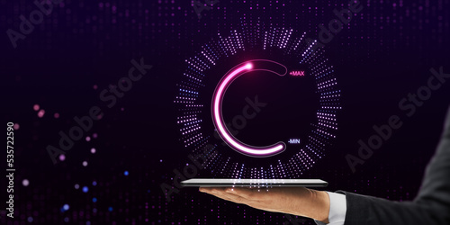 Close up of businessman hand holding tablet or smartphone with abstract glowing max and min scale hologram on dark background. Volume control and future concept.