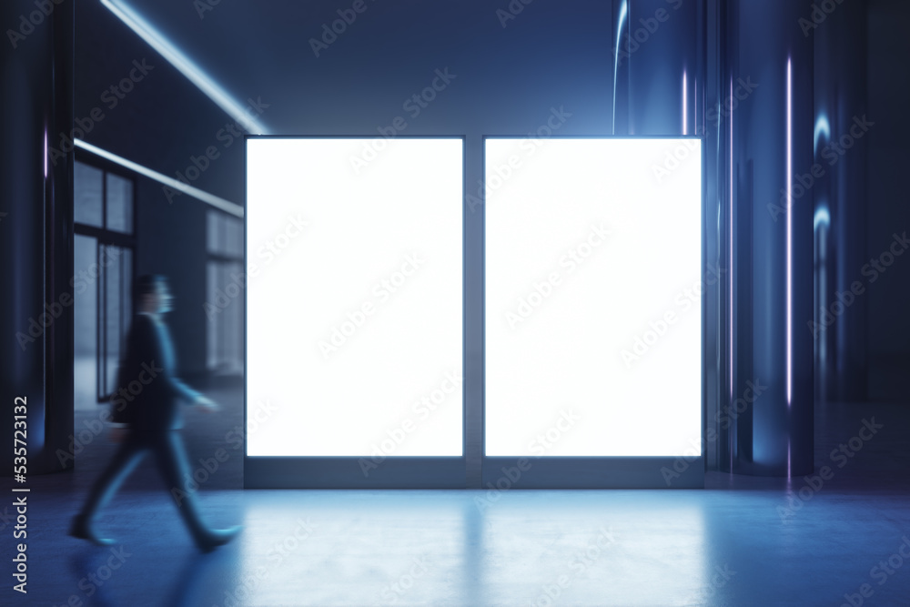 Walking businessman by blank white illuminated screens with place for your logo or text with glossy floor on dark empty room background, mock up Walking businessman by blank white illuminated screens with place for your logo or text with glossy floor on dark empty room background, mock up