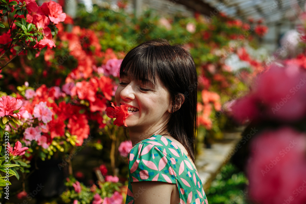 A girl in a green dress walks in a garden of azaleas of various bright colors A girl in a green dress walks in a garden of azaleas of various bright colors