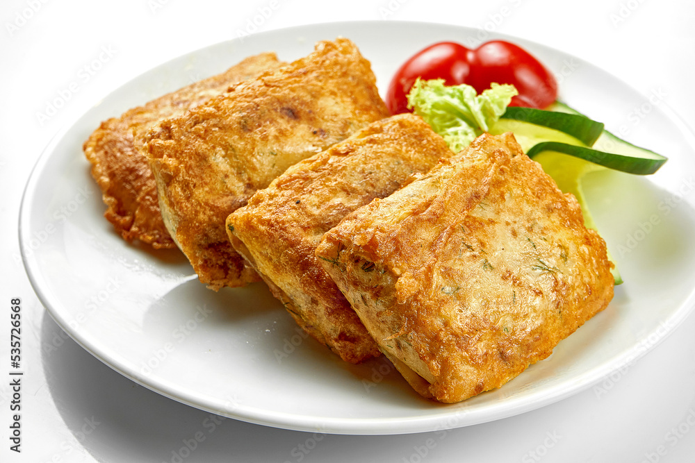 Crepes with stuffing and salad in a white plate. Close-up, selective focus. White background Crepes with stuffing and salad in a white plate. Close-up, selective focus. White background