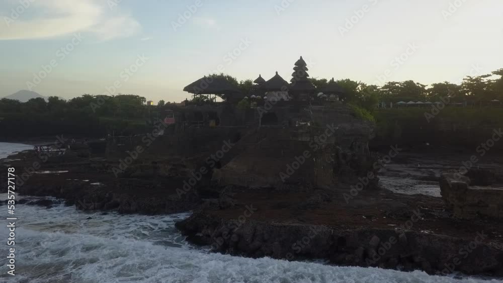 Ocean waves crash against rock base at Tanah Lot temple on Bali coast Ocean waves crash against rock base at Tanah Lot temple on Bali coast