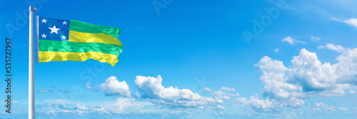 Sergipe - state of Brazil, flag waving on a blue sky in beautiful clouds - Horizontal banner photo
