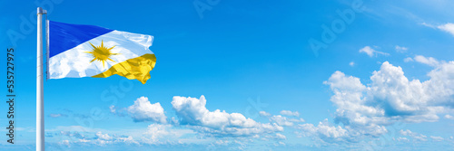 Tocantins - state of Brazil, flag waving on a blue sky in beautiful clouds - Horizontal banner photo