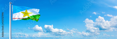 Roraima - state of Brazil, flag waving on a blue sky in beautiful clouds - Horizontal banner photo