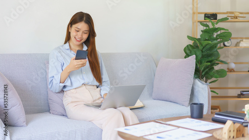 Remote business concept, Businesswoman reads marketing plan data on smartphone to working on laptop