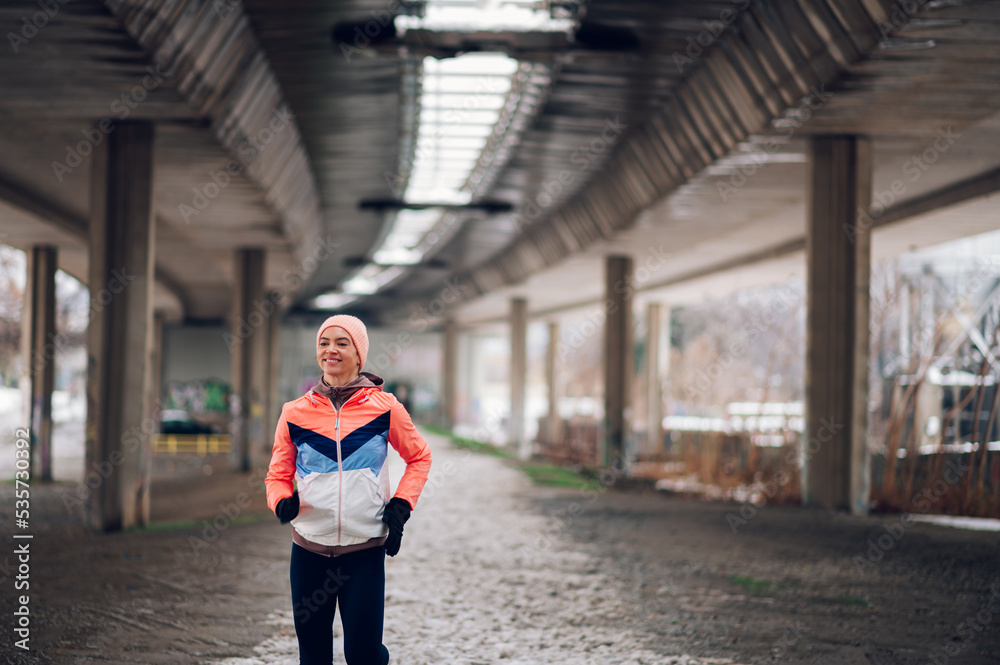 Woman running under the bridge on a cold winter day.