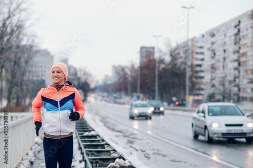 Woman in sportswear running on the bridge at winter