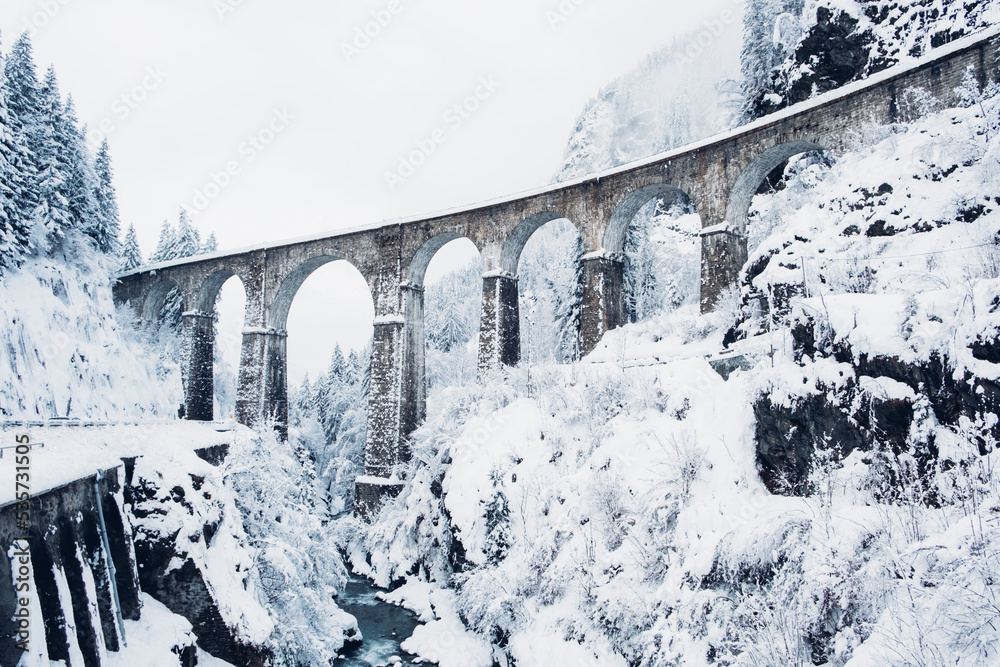 Fototapeta Mountain landscape with Sainte Marie bridge covered with snow in Les Houches, Chamonix valley, Eastern France. Viaduct bridge built to carry a railway over water.