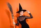 Photo of charming cheerful person hand touch headwear toothy smile hold broom isolated on orange color background