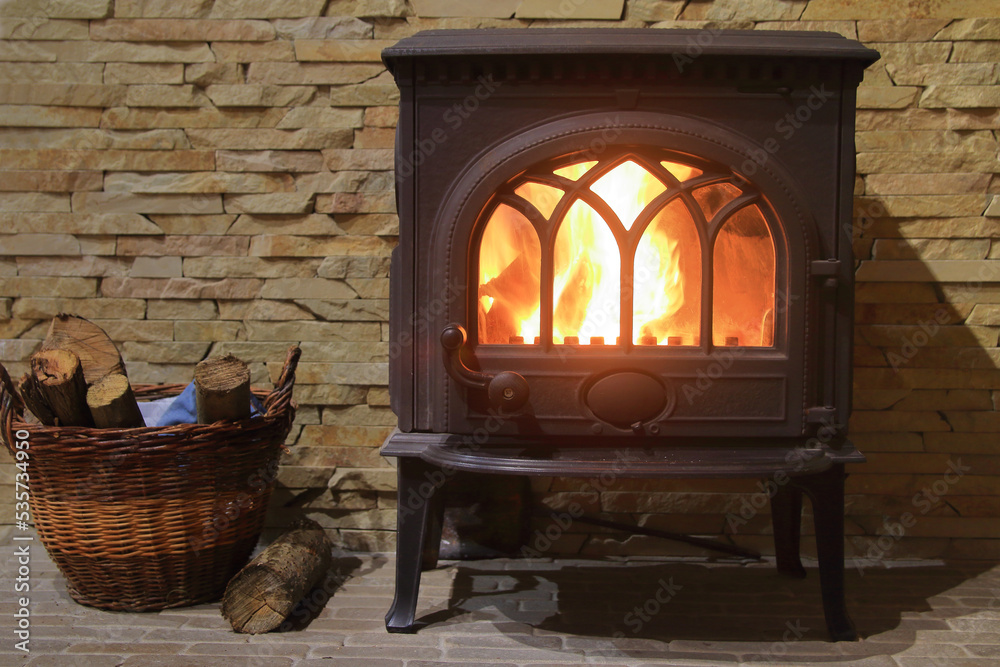 Cast iron stove with burning wood inside.