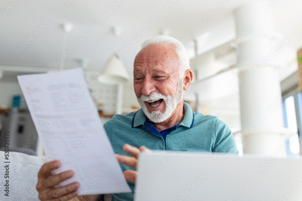 Surprised laughing happy old mature retired man looking through paper document, feeling excited analyzing financial information, getting taxes refund or bank loan approval at home. Surprised laughing happy old mature retired man looking through paper document, feeling excited analyzing financial information, getting taxes refund or bank loan approval at home.
