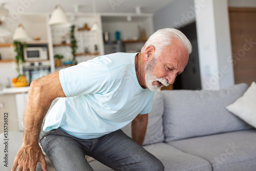 Senior elderly man touching his back, suffering from backpain, sciatica, sedentary lifestyle concept. Spine health problems. Healthcare, insurance