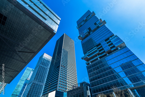 Bottom view of modern skyscrapers in business district against blue sky