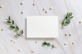 Vertical card on a marble table decorated with eucalyptus branches top view, Wedding mockup