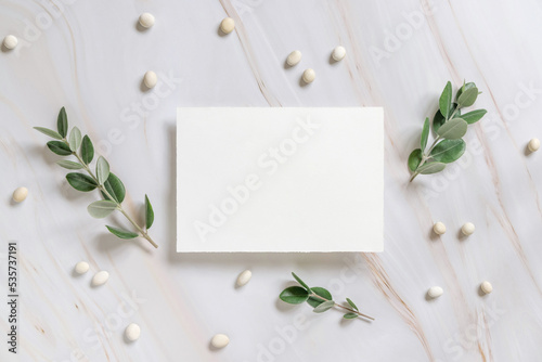 Vertical card on a marble table decorated with eucalyptus branches top view, Wedding mockup