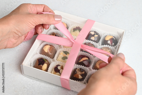 Closeup of a chocolate box present being wrapped. Woman packing home made candy in a gift box