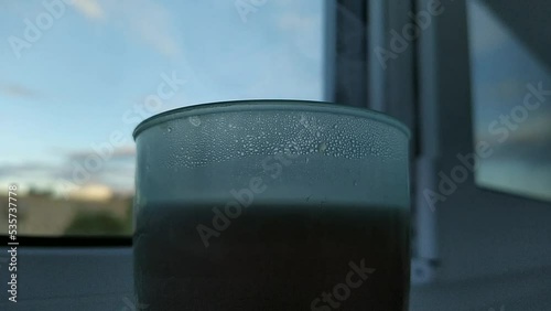 hot tea steam. steam from hot tea in a plastic cup against the background of a blurred balcony window