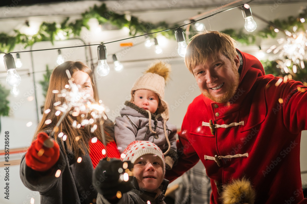 Happy large family celebrates christmas in nature and holds sparklers. Parents with three sons travels in a mobile home.