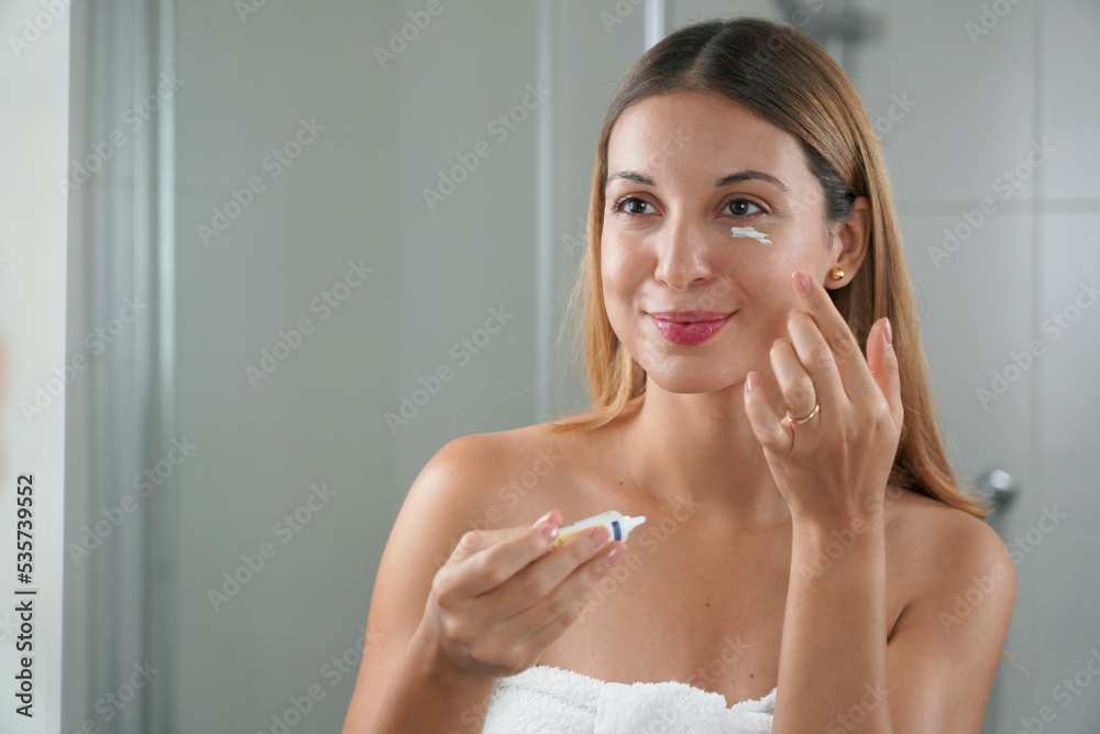 Skin care routine. Portrait of beautiful girl applying cream under eye with finger. Dark circles and anti-wrinkle concept. Skin care routine. Portrait of beautiful girl applying cream under eye with finger. Dark circles and anti-wrinkle concept.