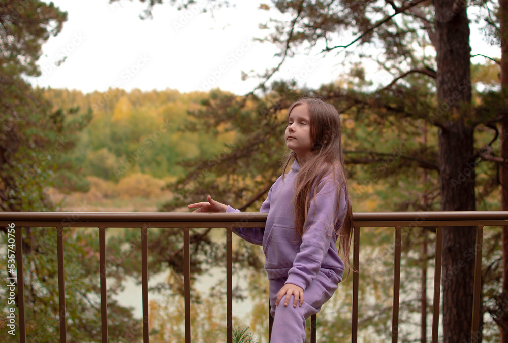 A girl in a purple suit, with long hair inhales fresh air in autumn in the forest. The concept of breathing, inhaling, relaxing A girl in a purple suit, with long hair inhales fresh air in autumn in the forest. The concept of breathing, inhaling, relaxing