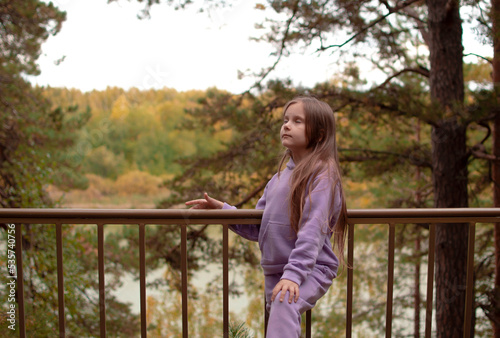 A girl in a purple suit, with long hair inhales fresh air in autumn in the forest. The concept of breathing, inhaling, relaxing