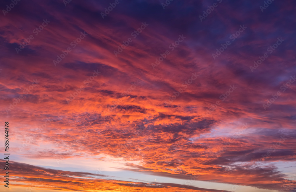 A vibrant sunset or sunrise sky with cloudscape in soft magenta, pink and orange tones as a background or texture