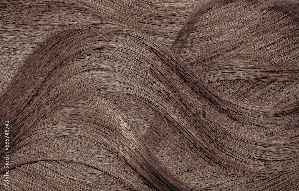 Naklejka premium Brown hair close-up as a background. Women's long brown hair. Beautifully styled wavy shiny curls. Hair coloring. Hairdressing procedures, extension.