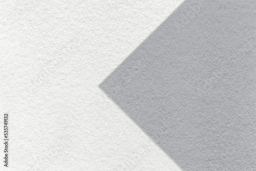 Texture of white paper background, half two colors with gray arrow, macro. Structure of craft grey cardboard.