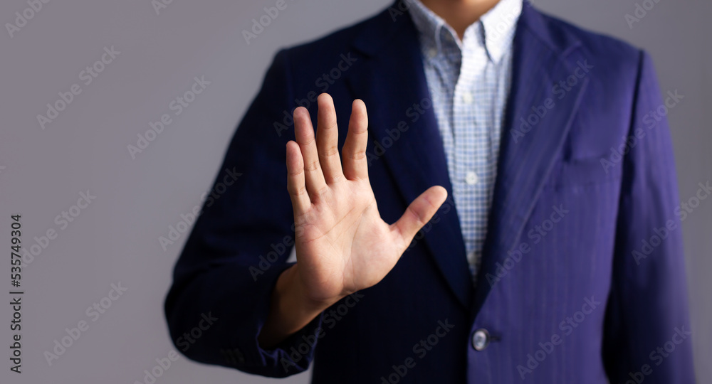 Obraz premium Young asian businessman in dark blue jacket posing hand touching on gray background.