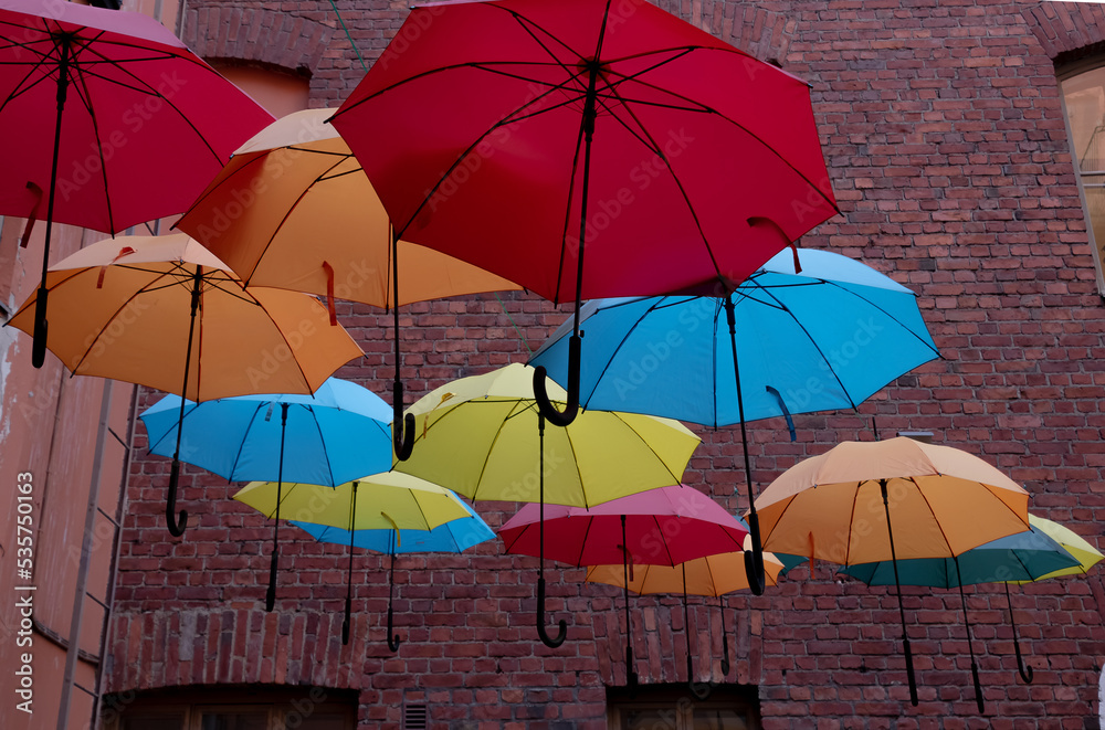 colored umbrellas in the courtyard of a brick house, brick wall