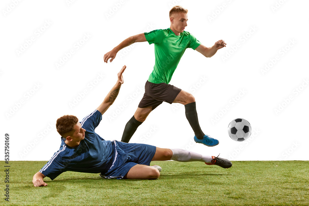 Soccer football players tackling for the ball on grass flooring over white background. Concept of sport, action, competition, football match
